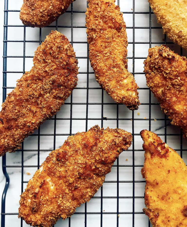cooked nacho flavored chicken tenders on top of black cooling grate.