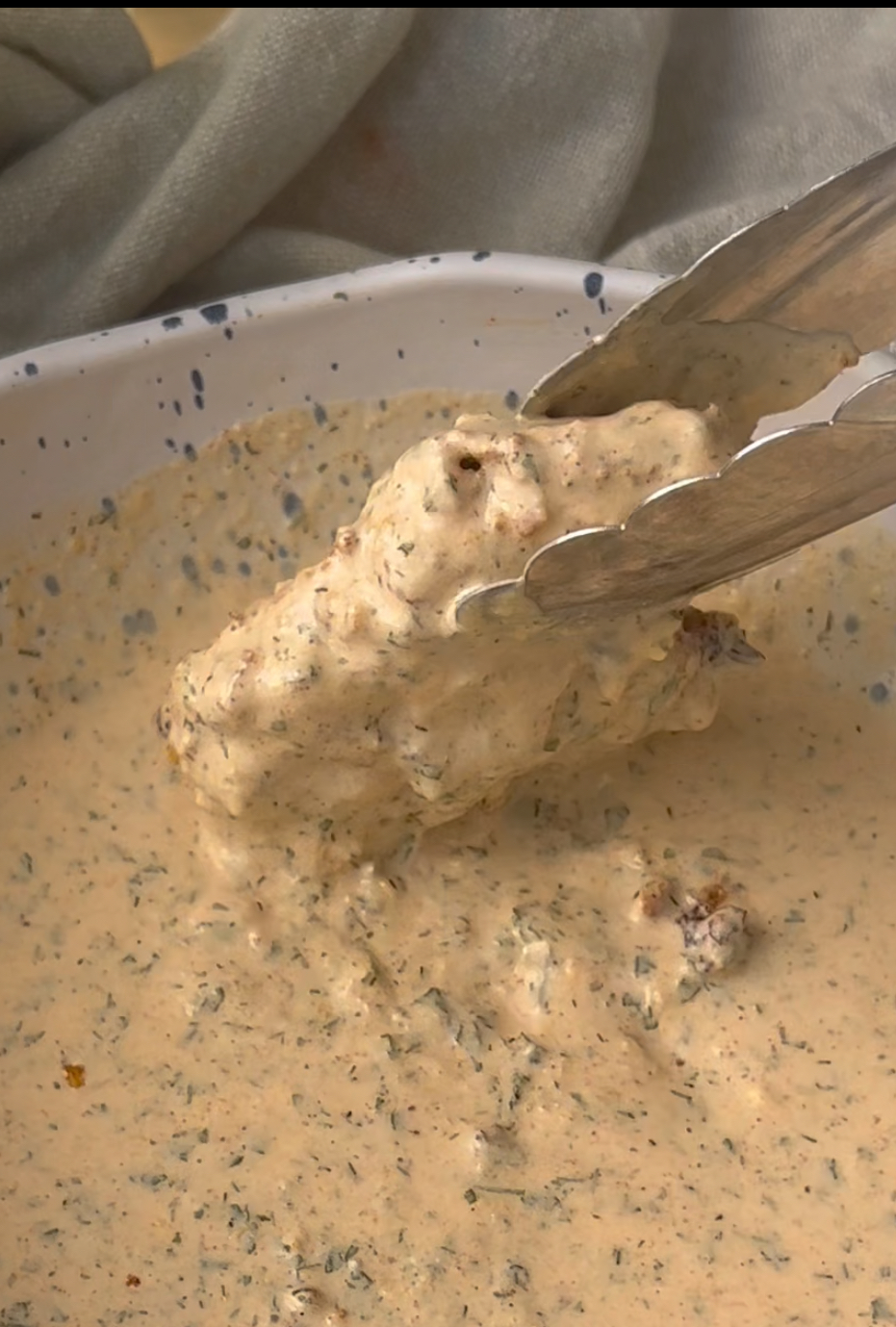 dipping a boneless wing into the ranch Parmesan sauce to coat it