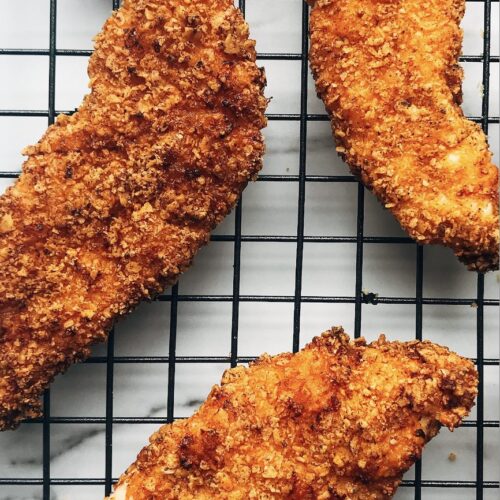 cooked chicken tenders on top of a black cooling grate