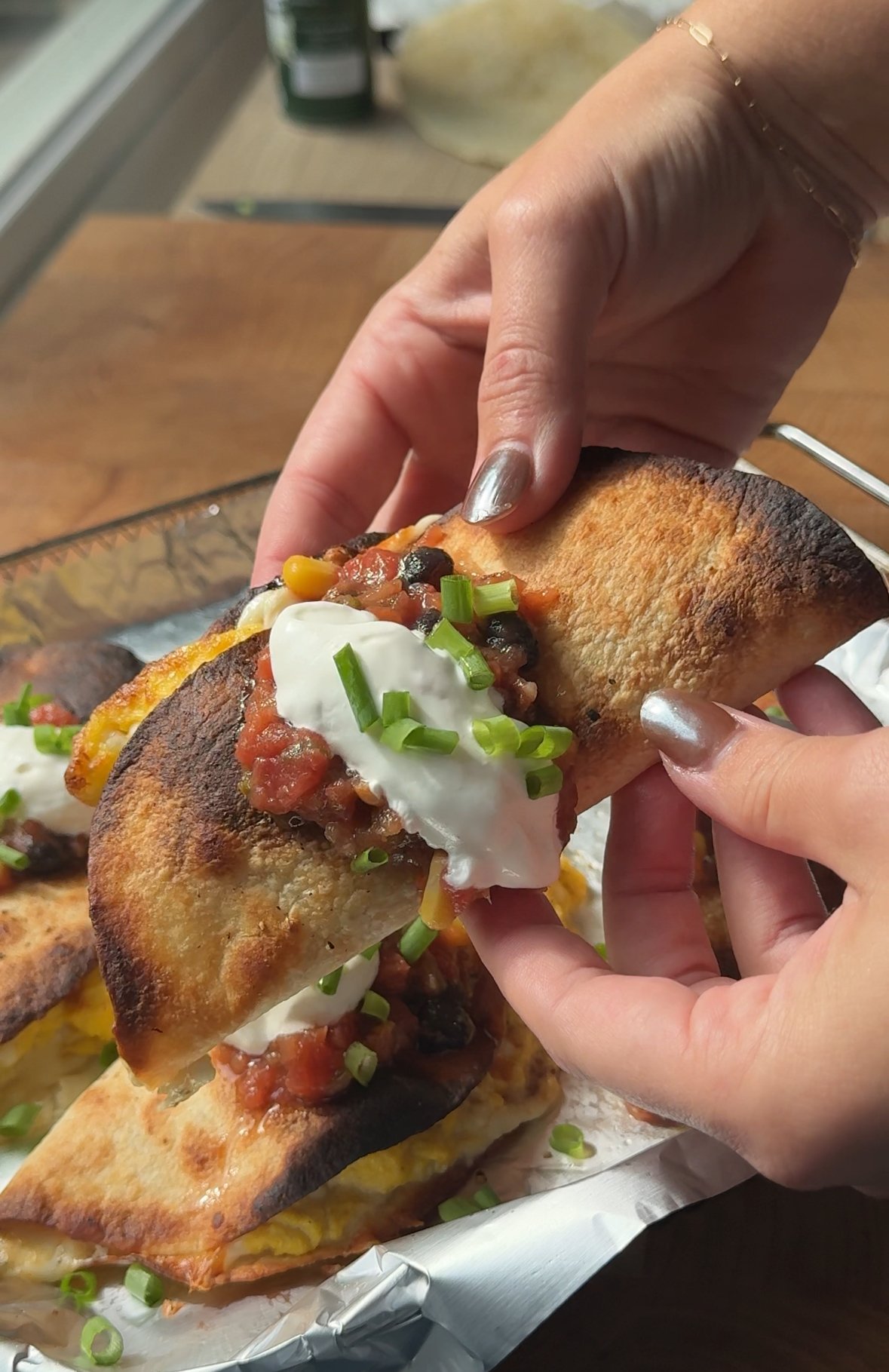 breakfast taco being held in hands with salsa and sour cream on top