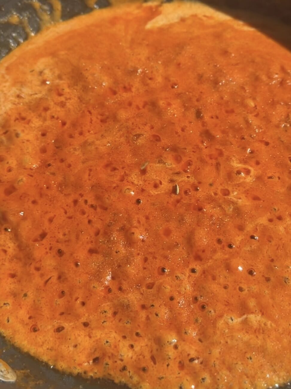 Spicy red sauce thickening in pan.