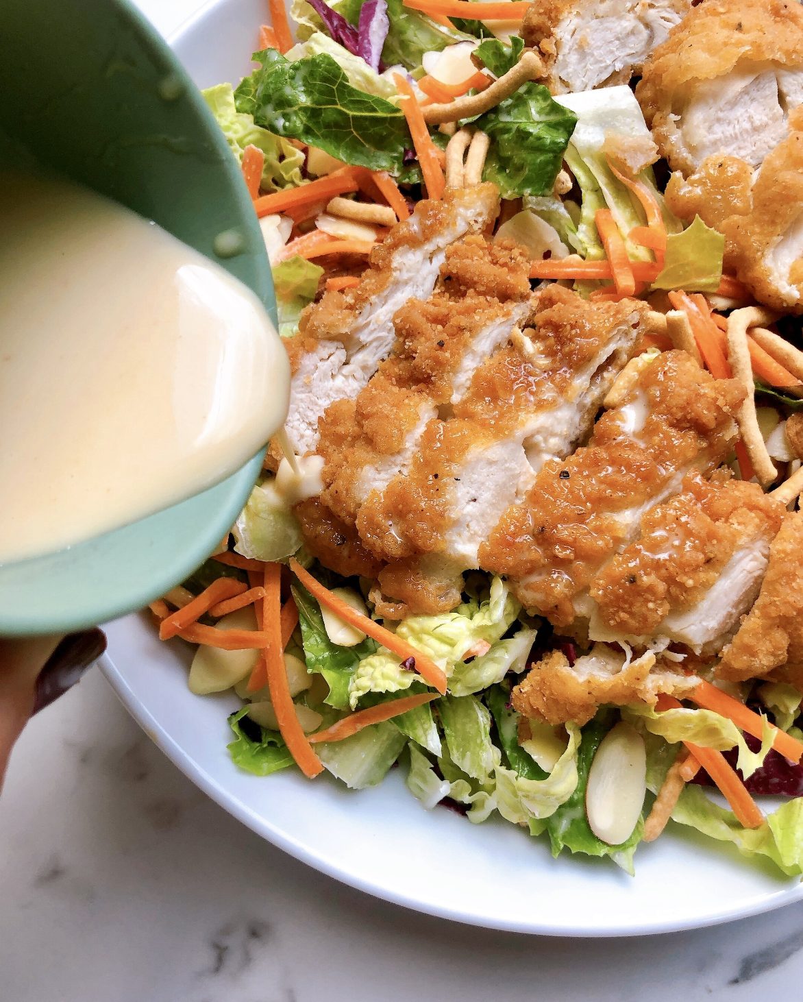 pouring dressing onto the copycat applebees oriental chicken salad