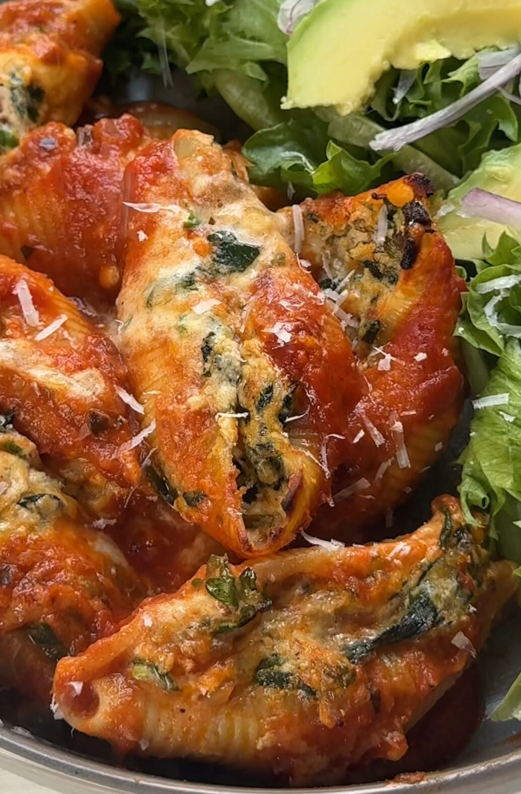 cooked butternut squash ricotta and spinach stuffed shells next to a green salad topped with avocado