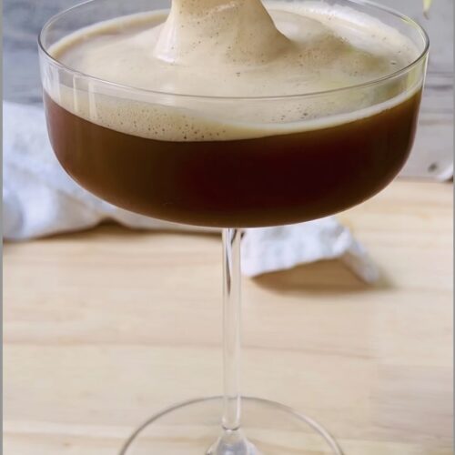 Foam being poured on top of a homemade espresso martini with gold spoon