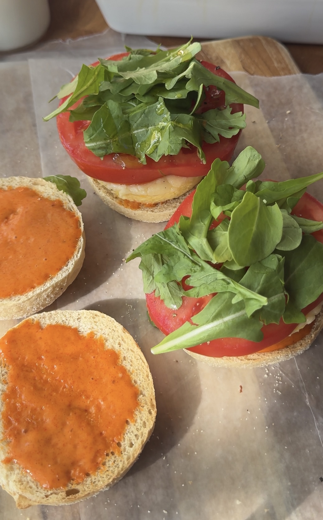 spicy aioli on one side of the english muffin and arugula and tomato on top of the egg on the other side