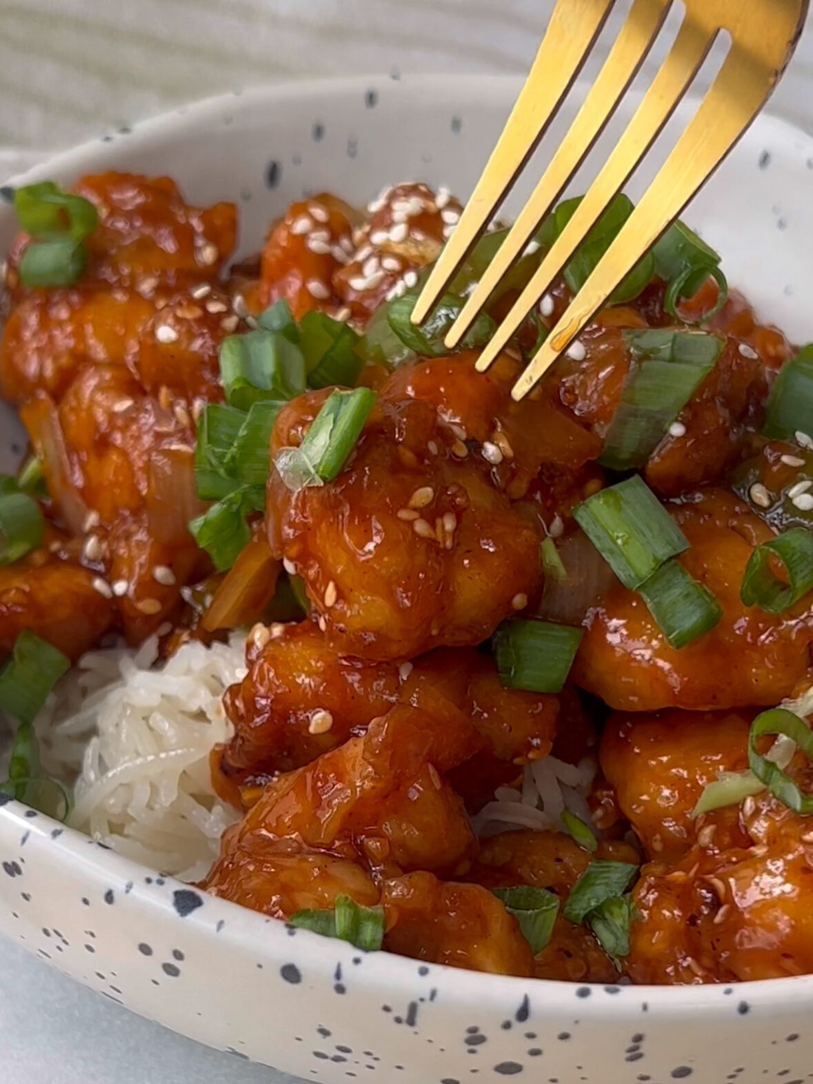 Sesame chicken over coconut rice with green onions on top