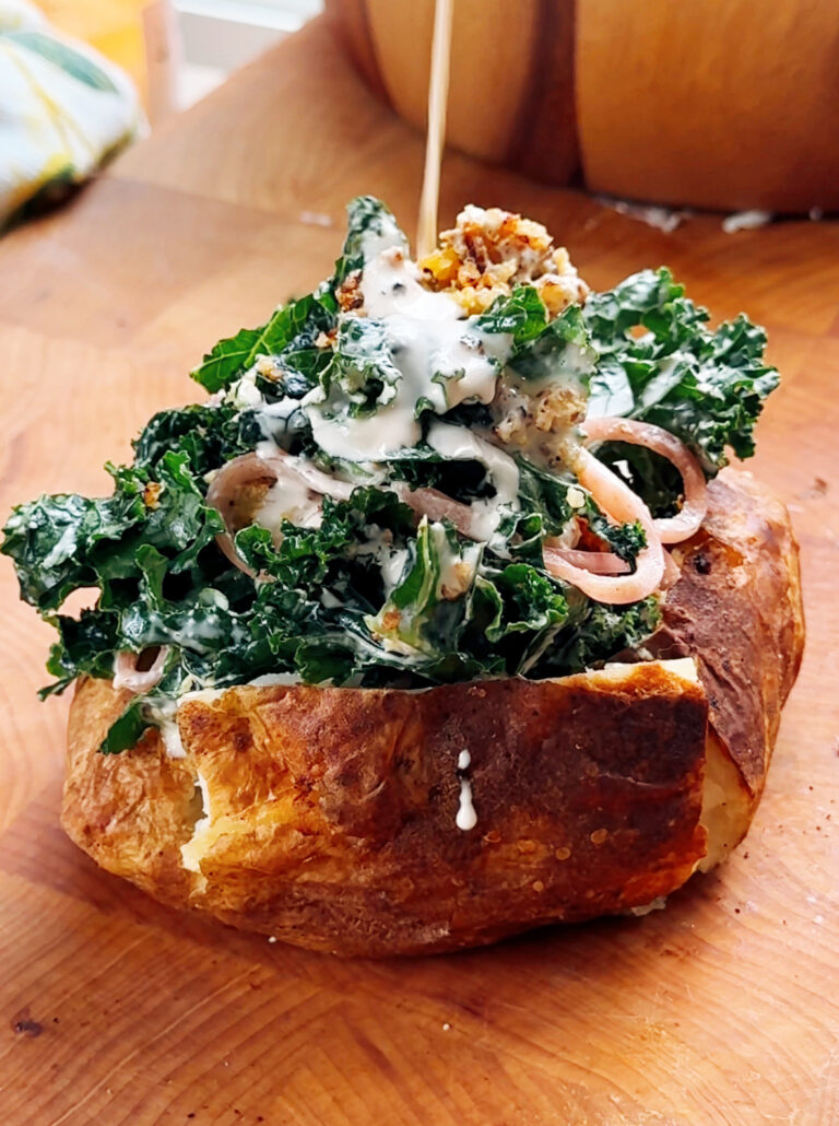 A stuffed caesar salad baked potato with dressing on top.
