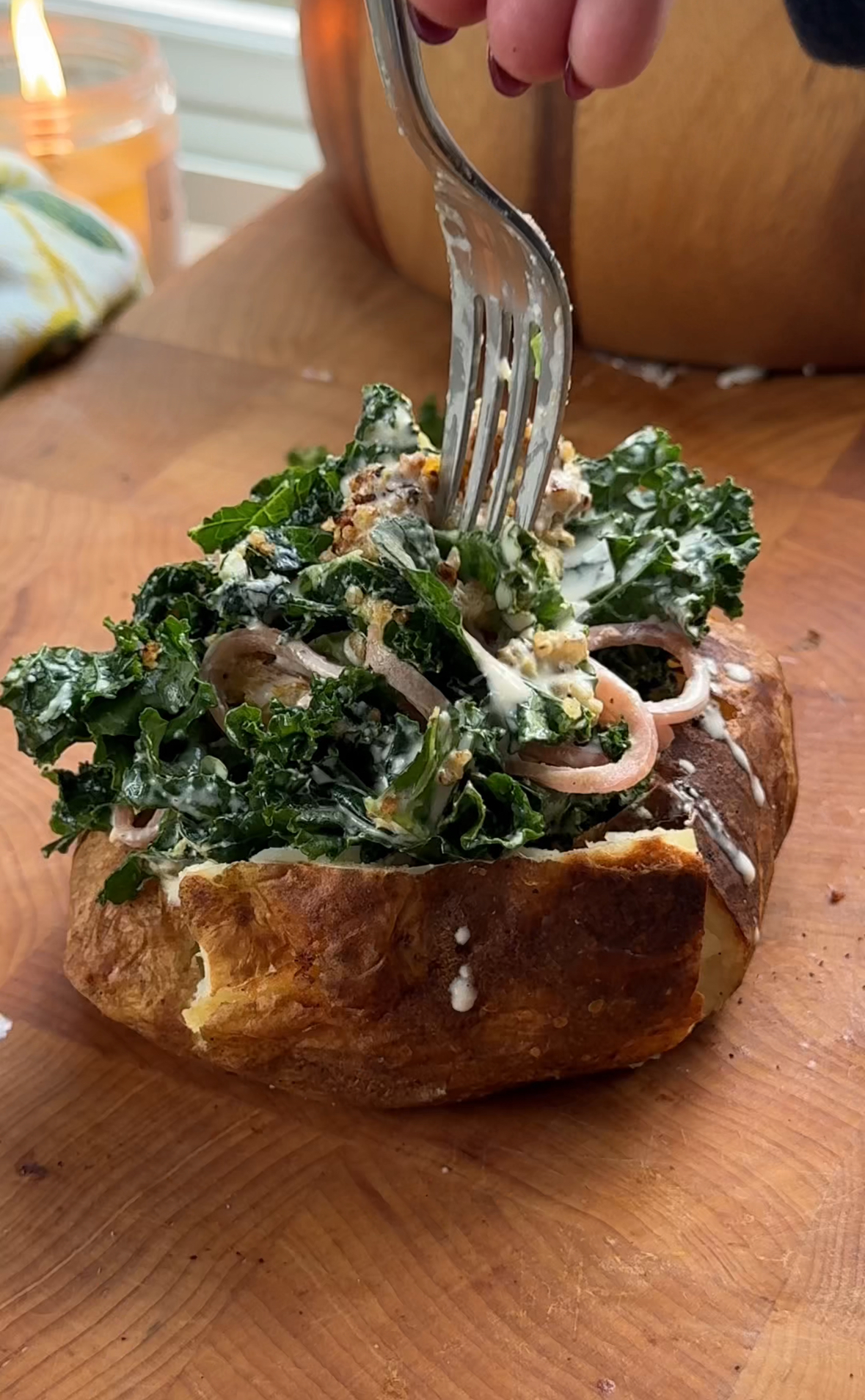 Fork going into baked potato stuffed with Caesar salad, avocado, pickled red onions, and crispy quinoa.”