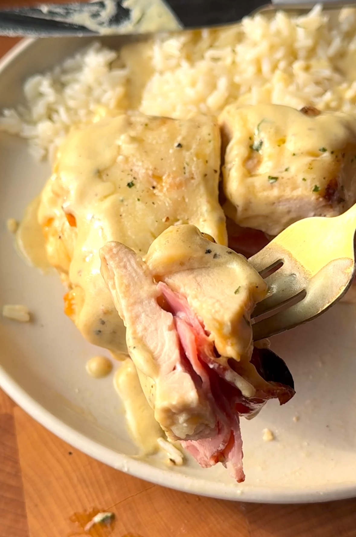 a piece of chicken cordon bleu on a fork with rice on a plate