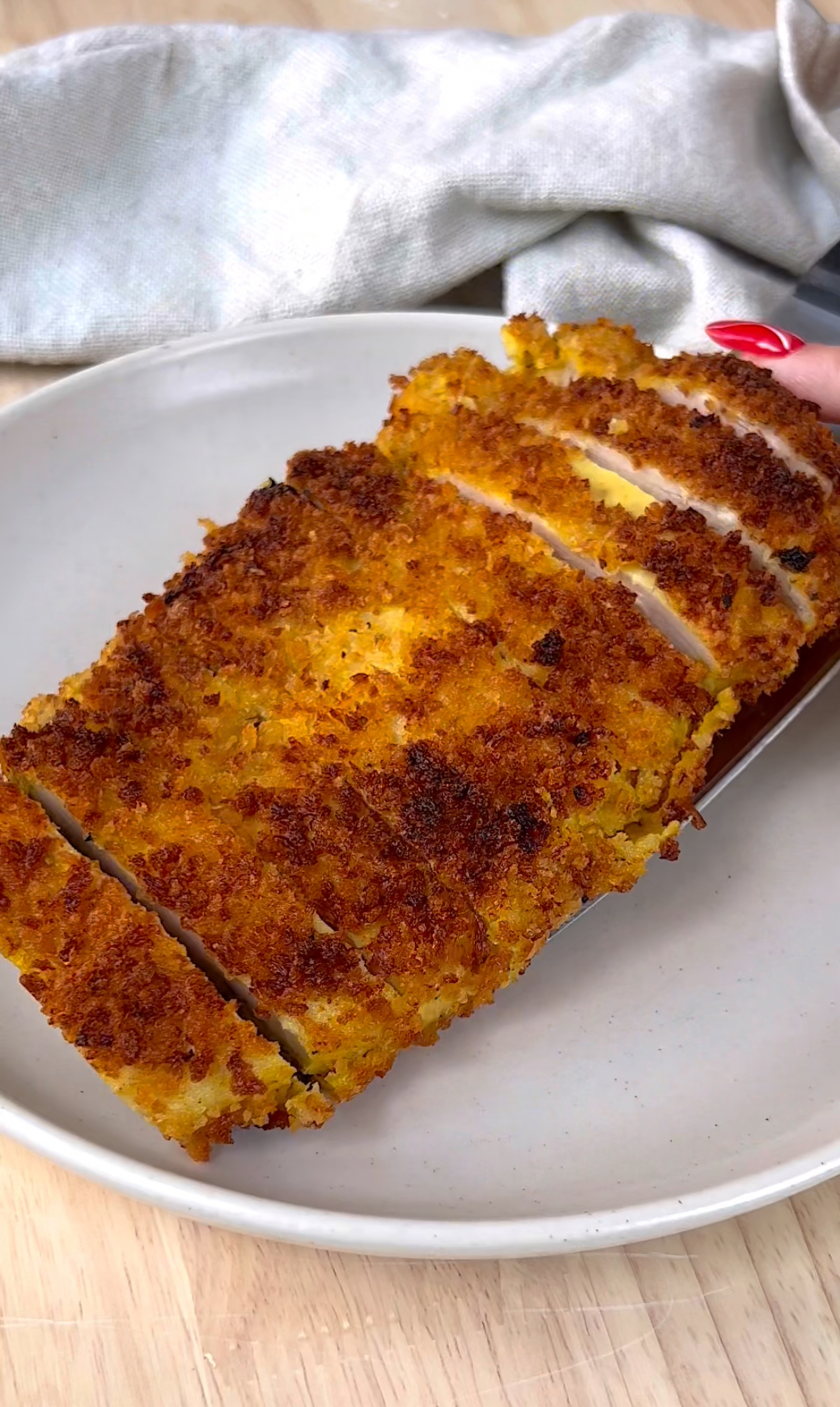 chicken cutlet cut into pieces being put on a white plate