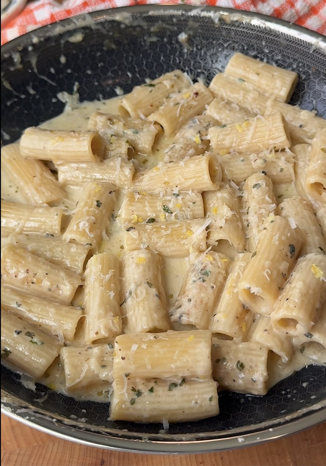 rigatoni in a lemon cream sauce in a pan topped with Parmesan cheese