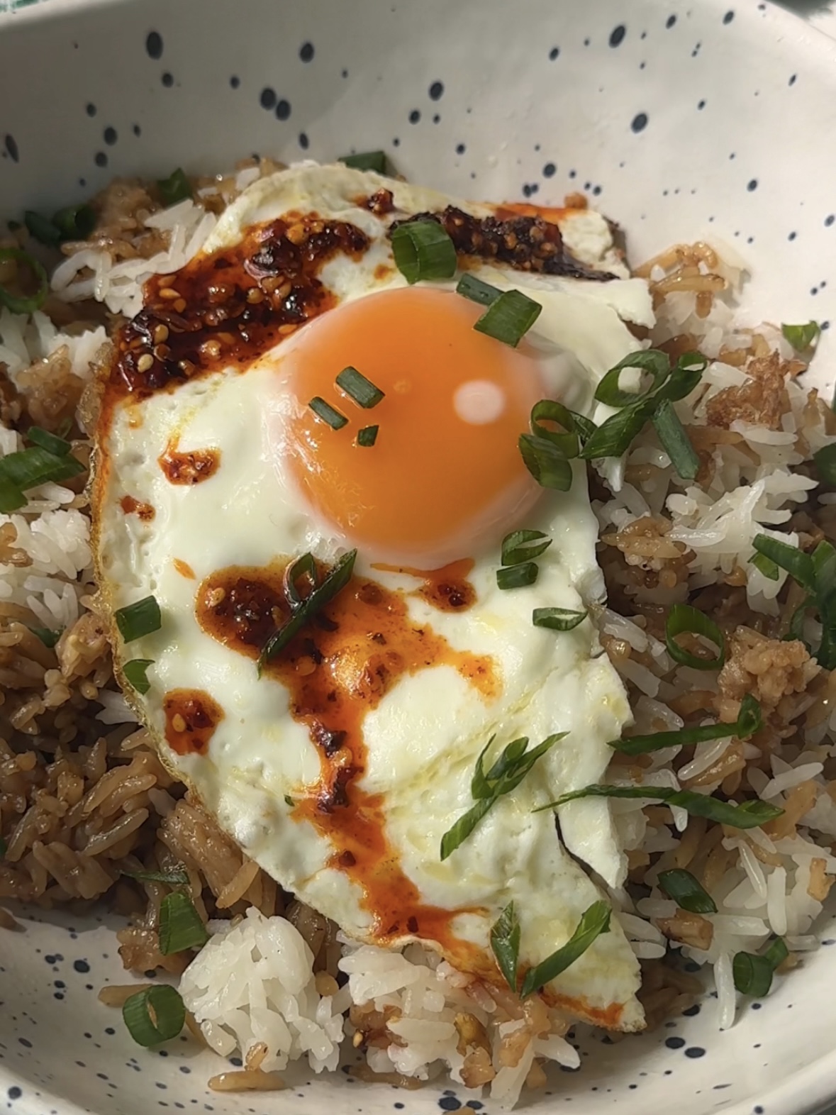 fried egg over leftover rice topped with chili crunch and scallions