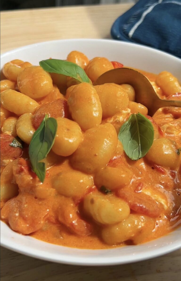 creamy gnocchi in a buratta tomato sauce in a white bowl with a gold spoon