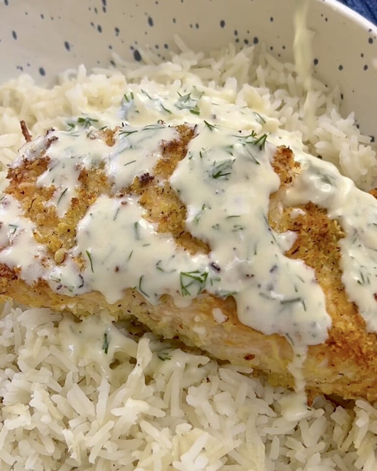 crispy salmon on top of white rice drizzling a yogurt dressing on top