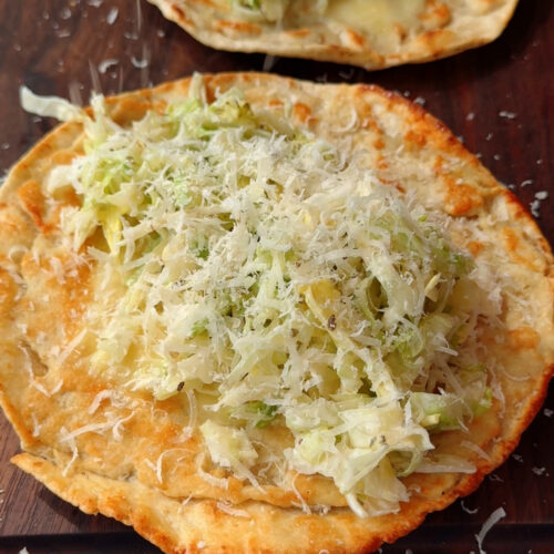 chicken smashed taco on top of cutting board with grinder slaw and Parmesan on top