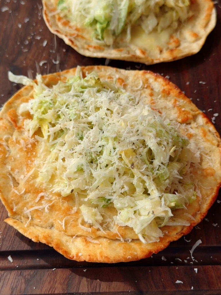 chicken smashed taco on top of cutting board with grinder slaw and Parmesan on top