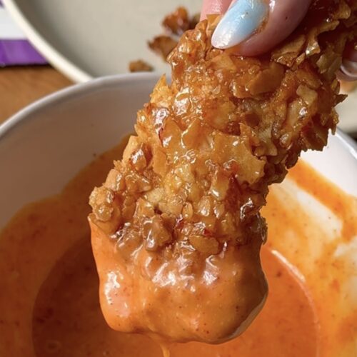 chicken tender dipping into orange sauce