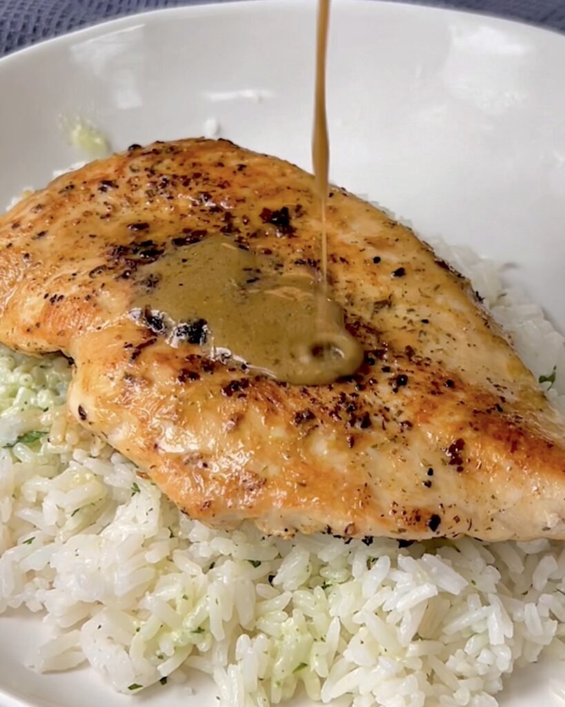 pan sauce being poured on top of chicken over rice